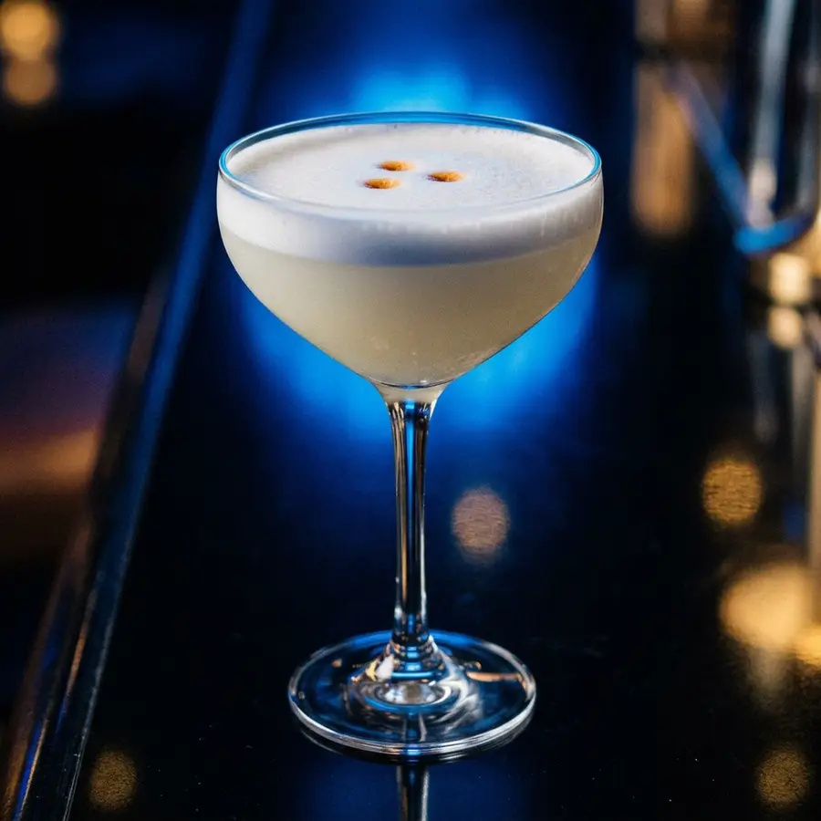 Un pisco sour recién servido, con la espuma y las tres gotas de amargo